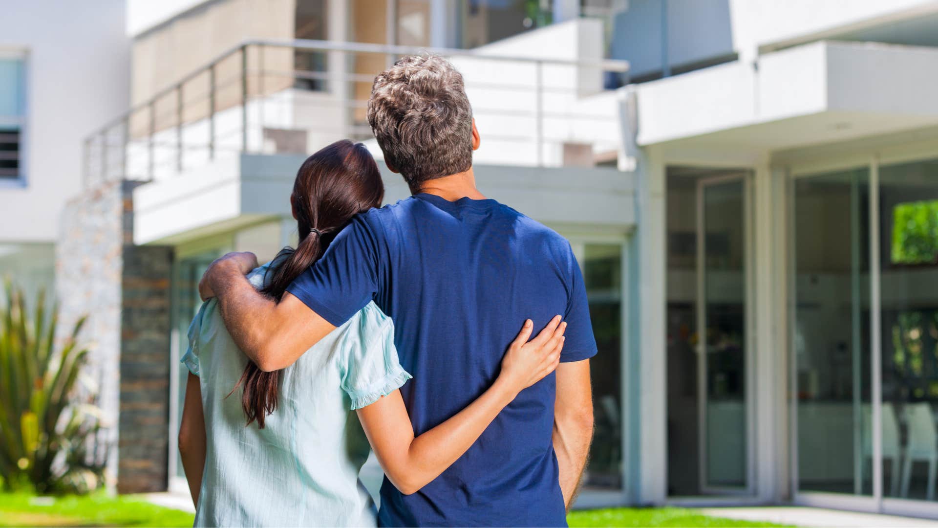 couple staring at big home hugging each other
