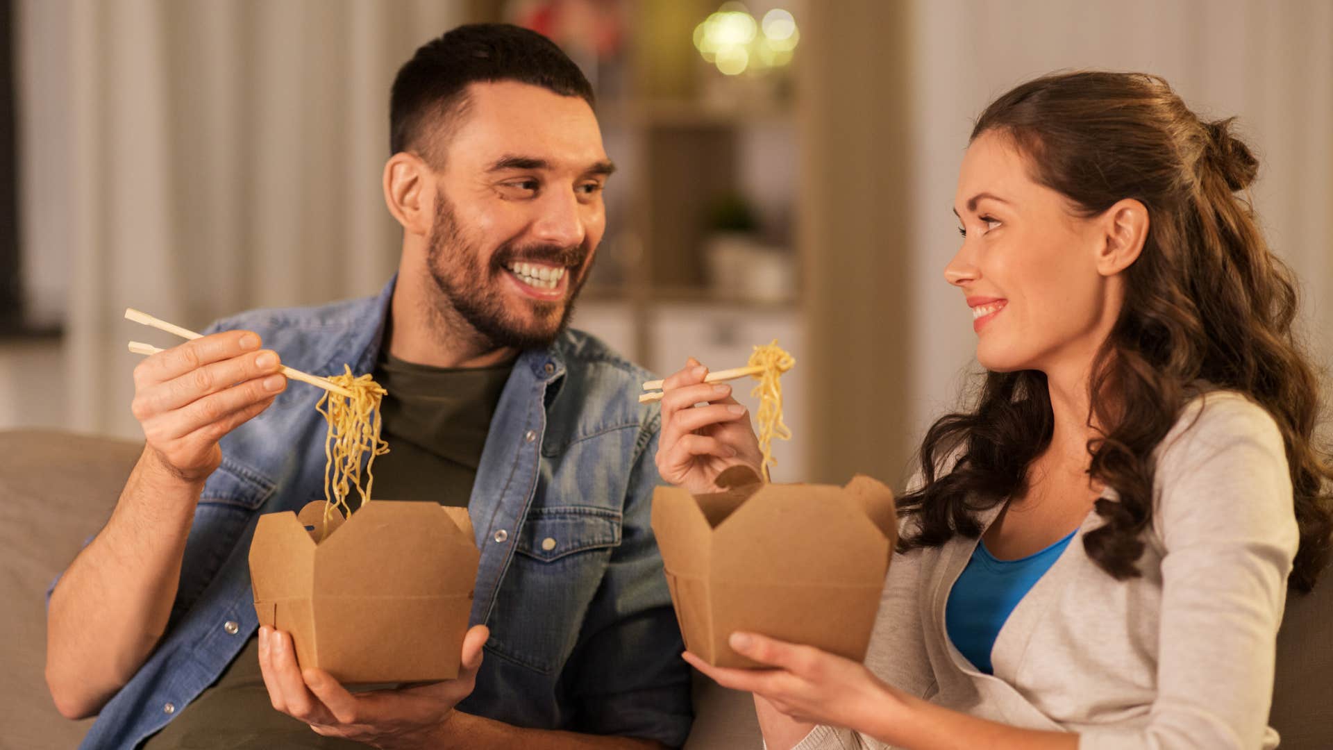 couple eating takeout together on the couch