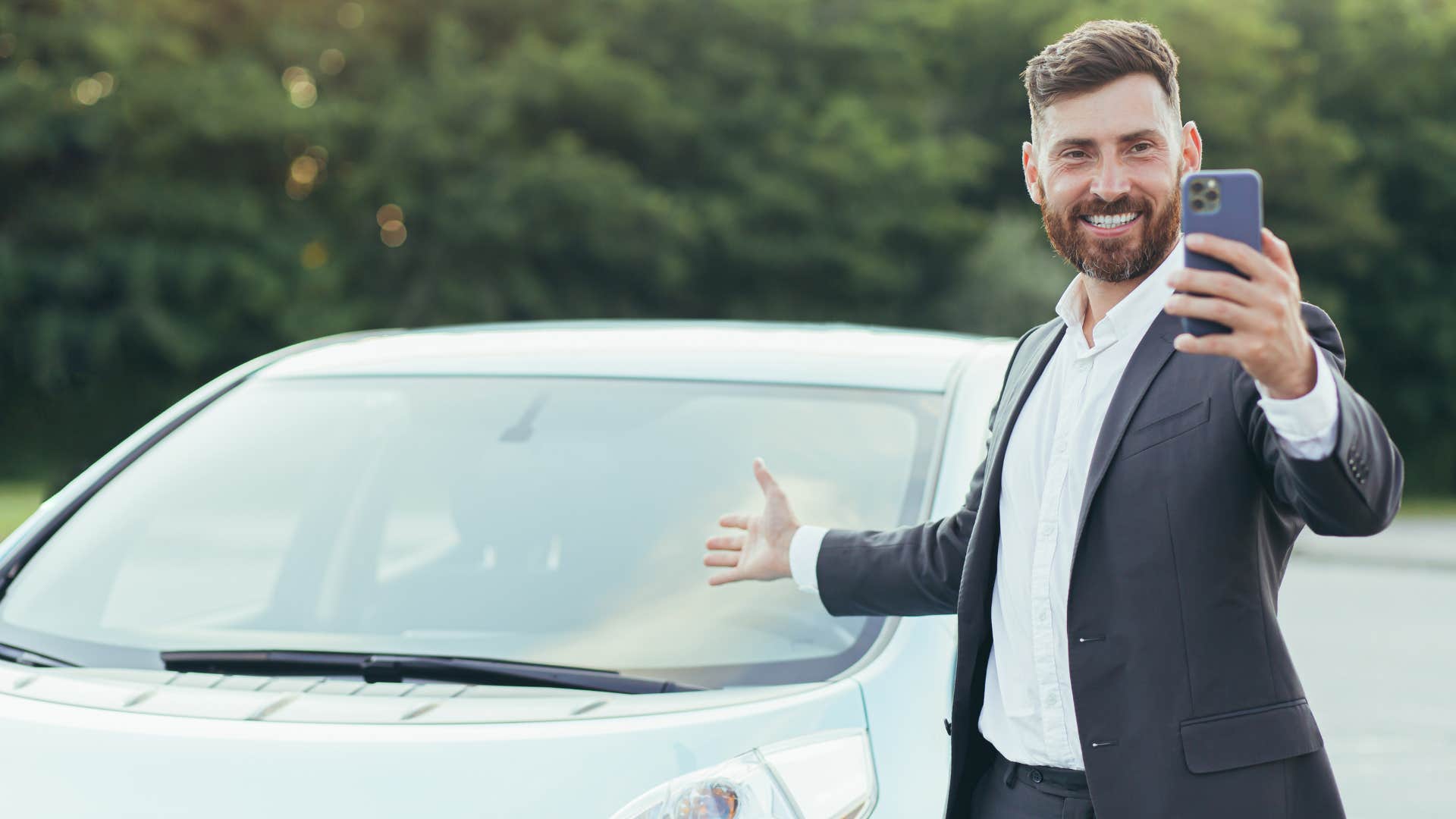 businessman taking a selfie in front of his car
