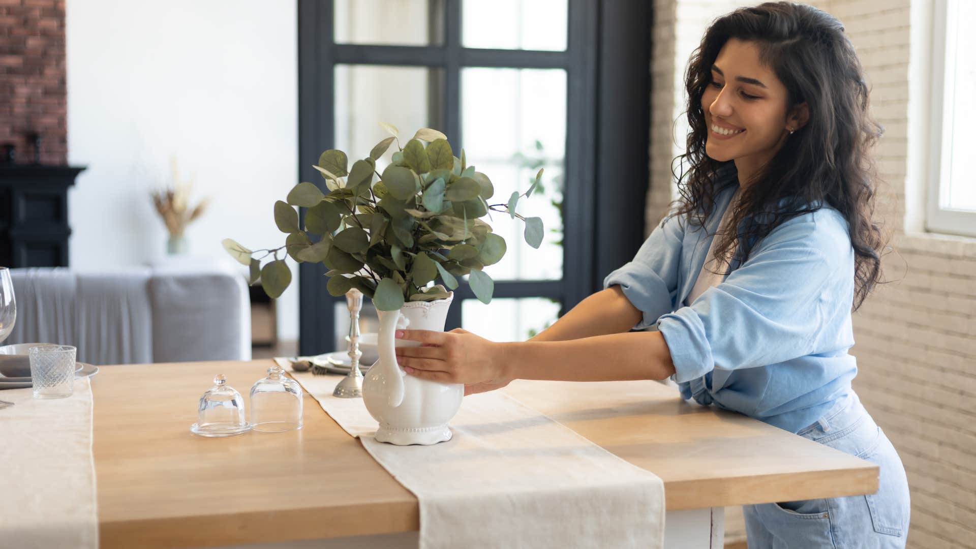 woman fixing home decorations on table as she smiles