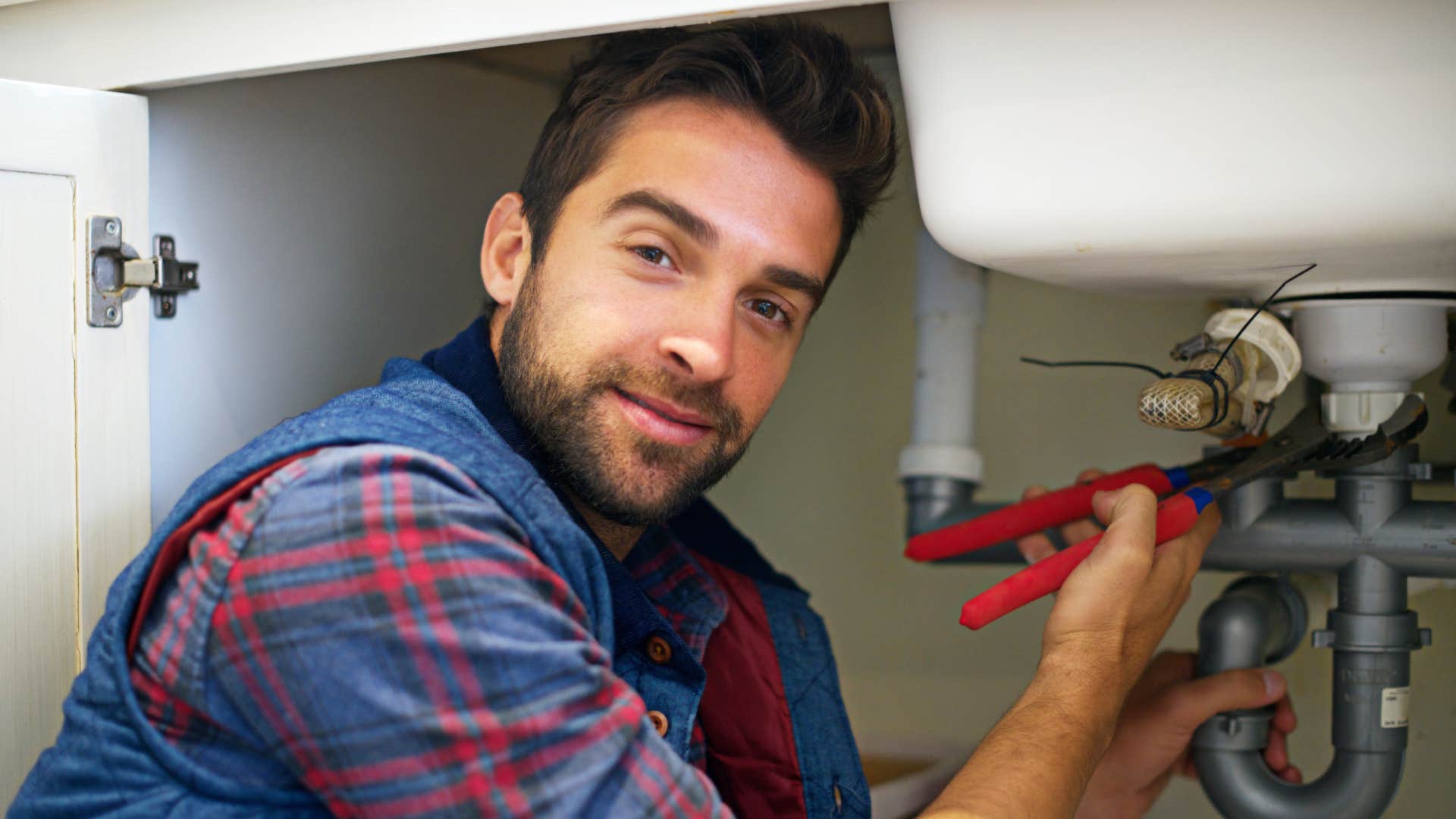 a man fixes his own plumbing after a leak instead of calling a professional