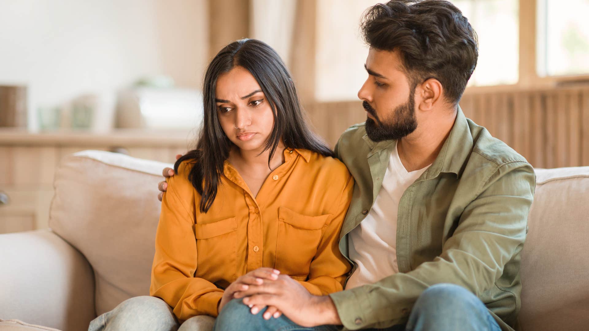 man telling his upset partner he doesnt want to hold her back