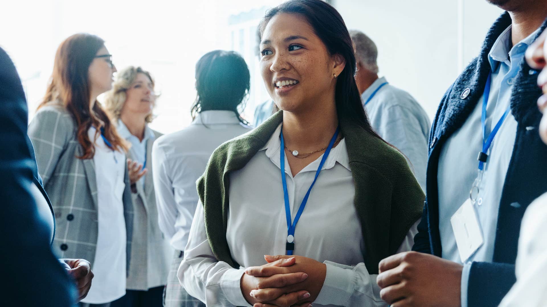 woman fake smiling and looking around at networking event
