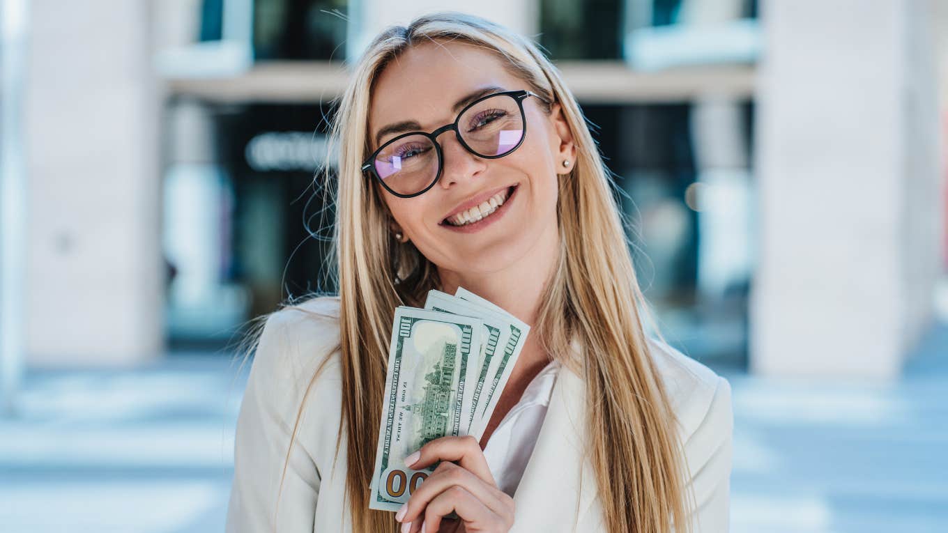 Things People With Quiet Wealth Never Waste Money On rich woman holding a wad of cash