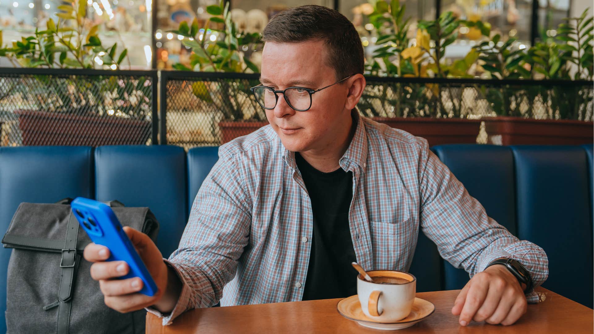 man eating overpriced airport food at a table looking at his phone