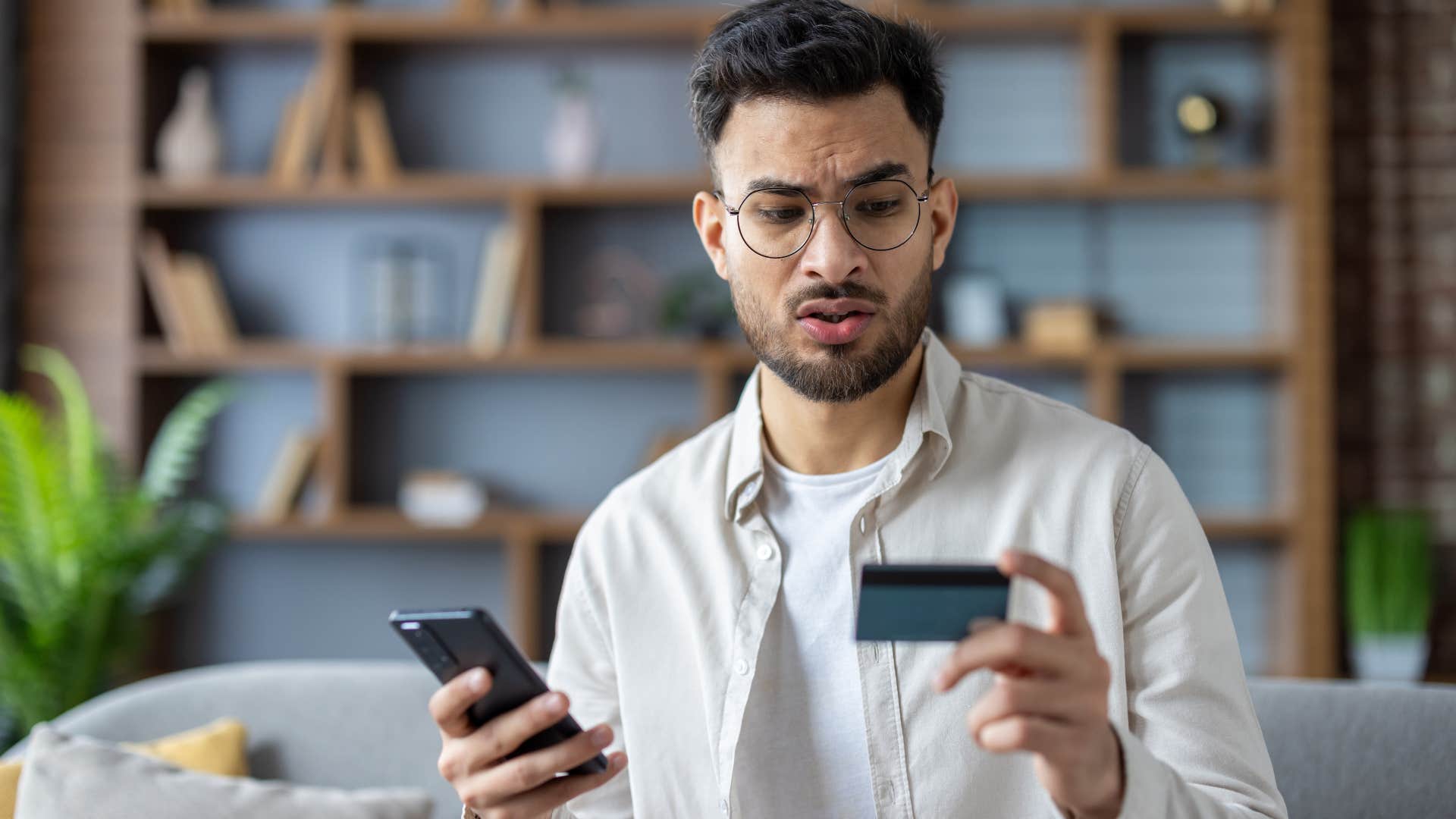 frustrated confused gen z man looking at overpriced concert tickets on his phone
