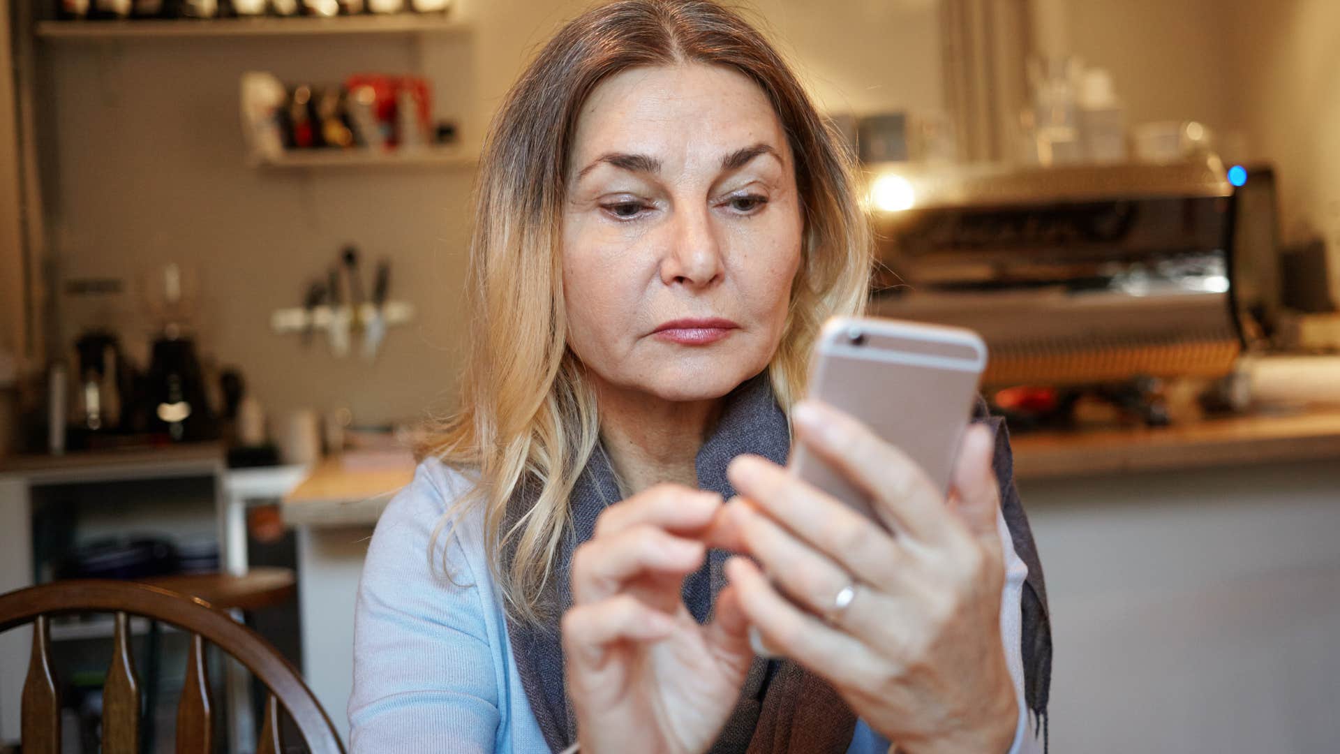 boomer woman looking at scam calls and texts on her phone