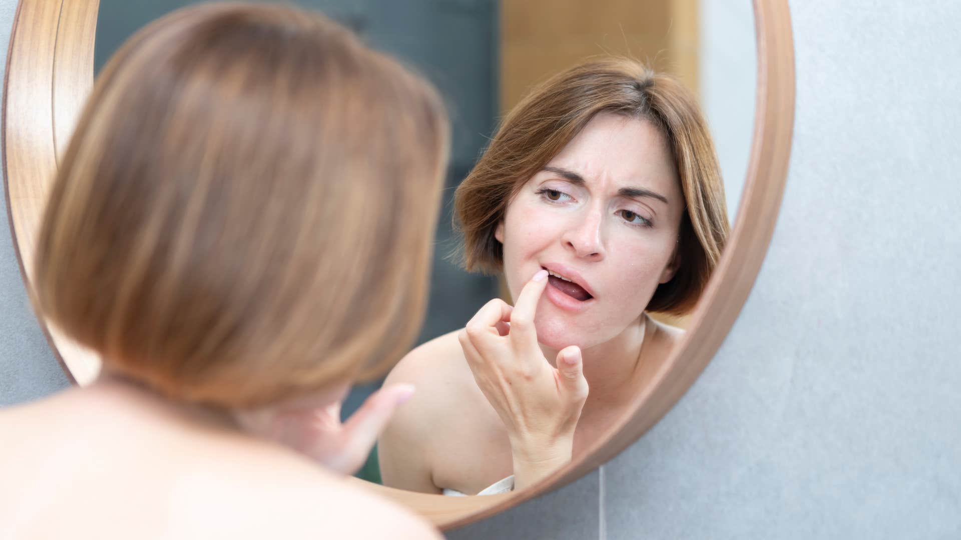 woman checking reflection in bathroom mirror
