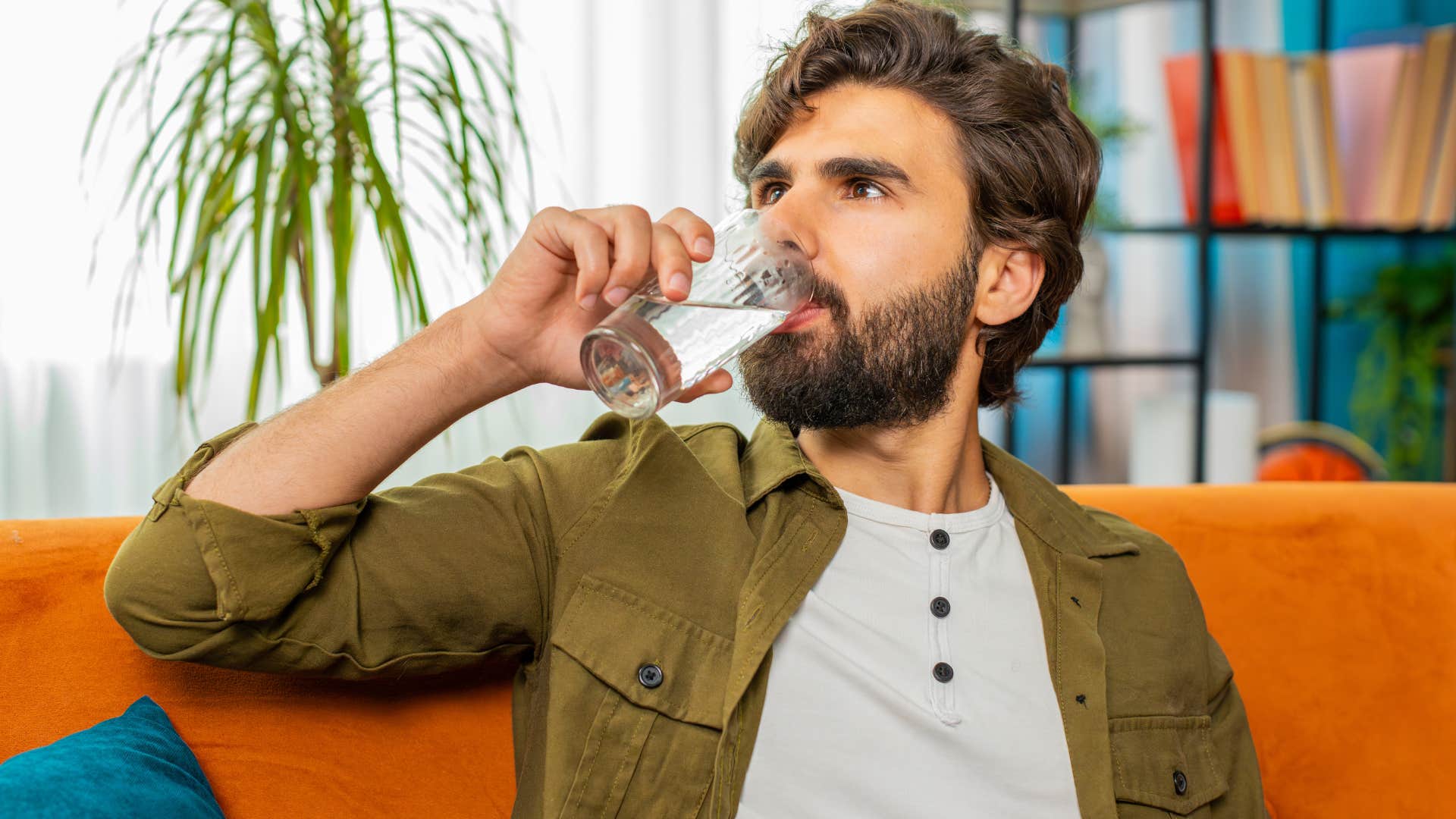 man drinking glass of water as guest in someones home