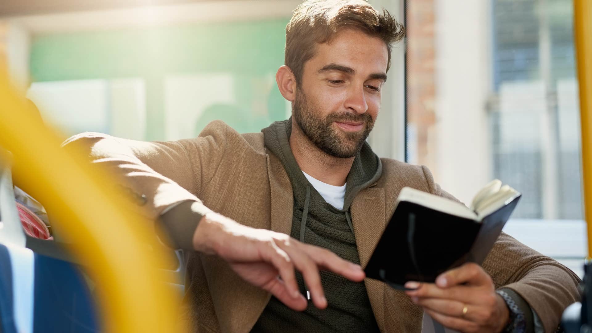 man reading a book on a public bus