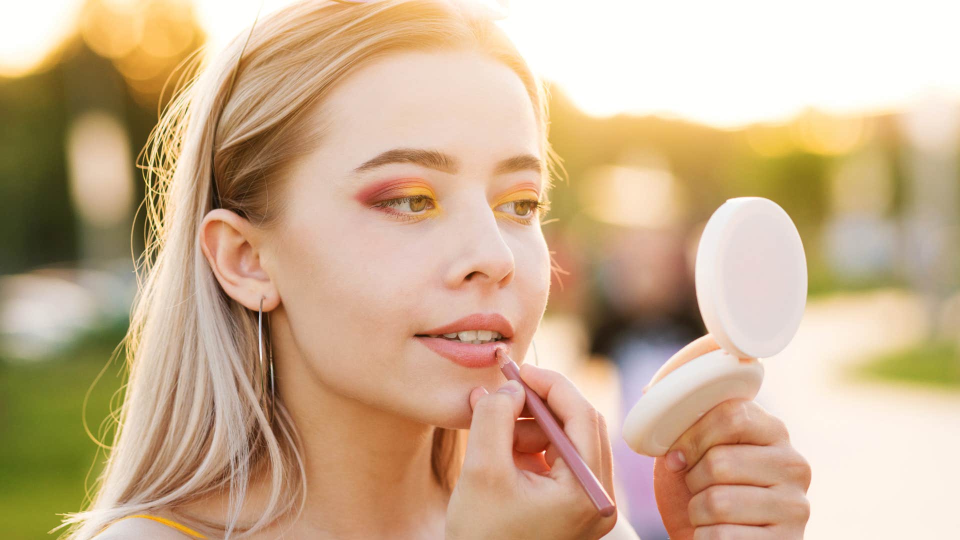 woman fixing her makeup using a compact mirror