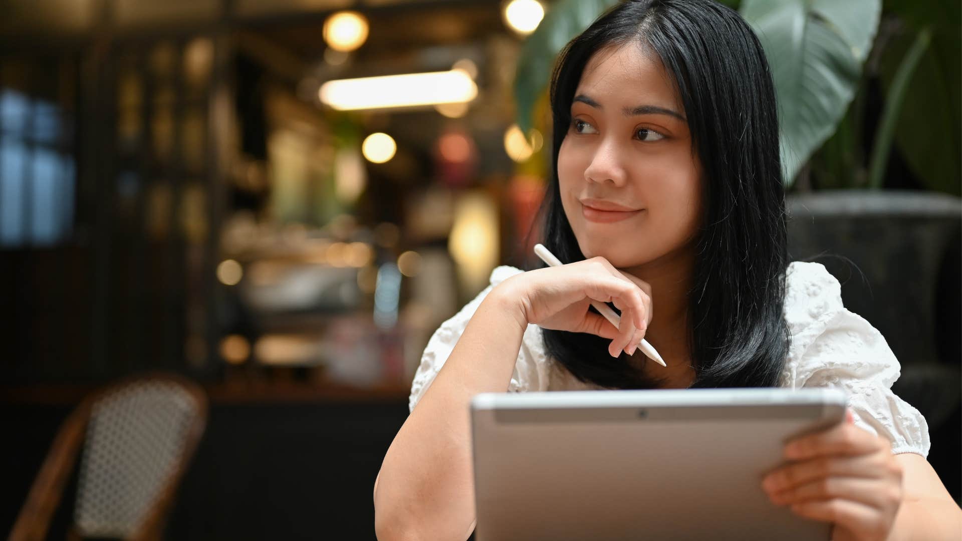 woman holding creative supplies and smiling in a coffee shop