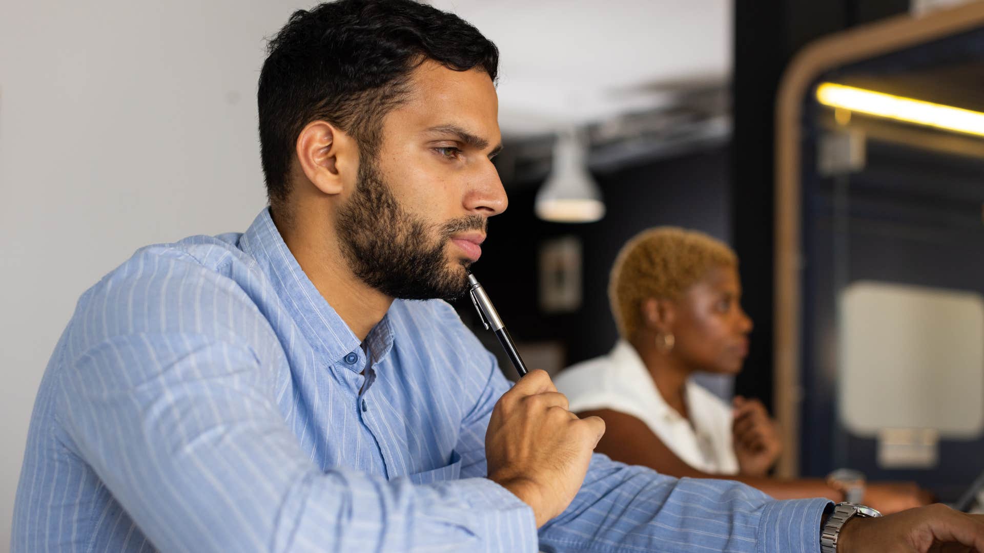 man holding pen to fidget with while focusing at work