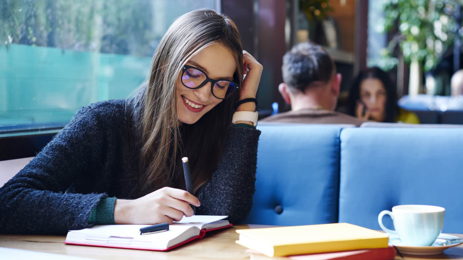 woman smiling and writing in a small notebook