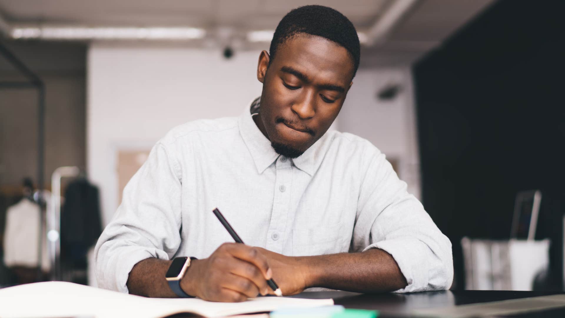 man writing in his planner at work
