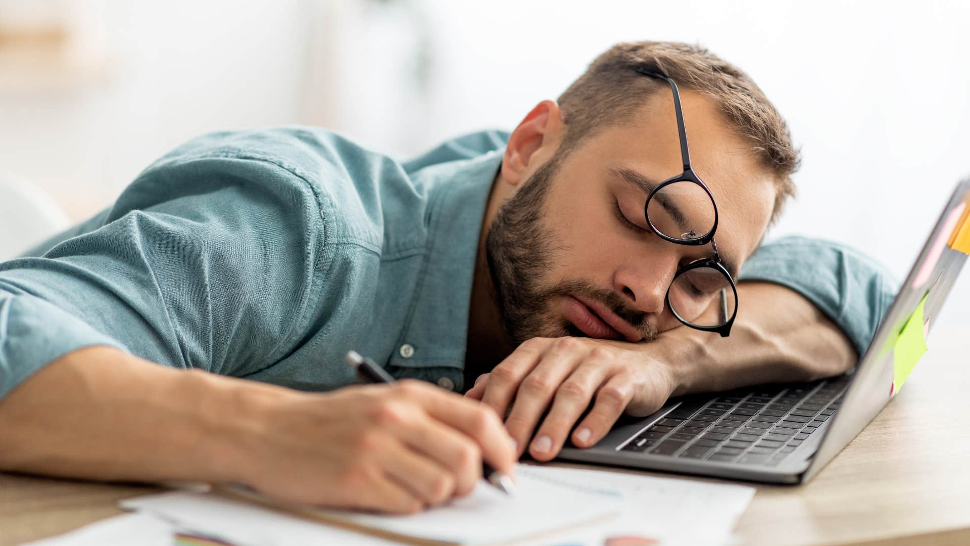 man romanticizing burnout while asleep at his desk exhausted