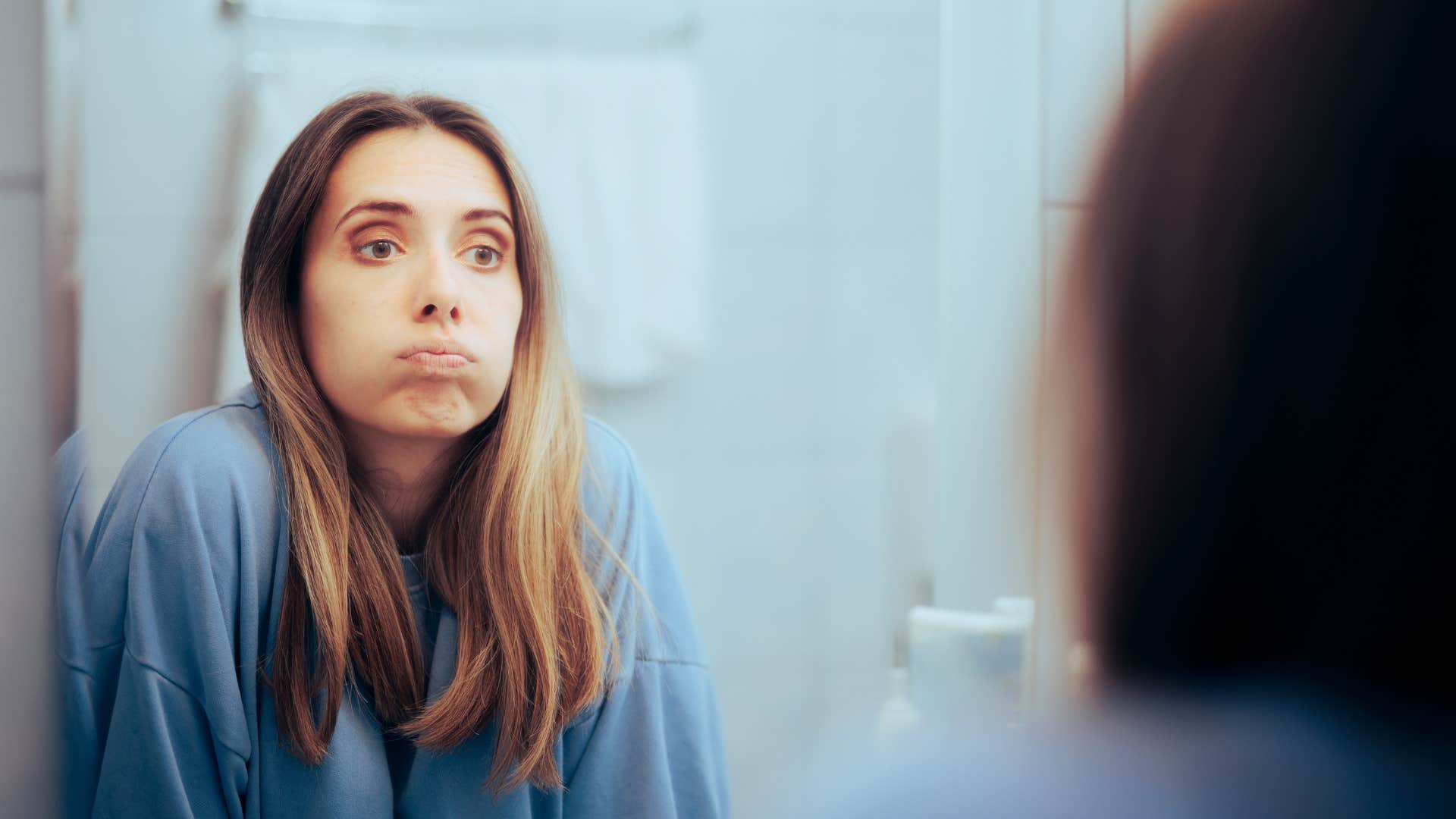 overwhelmed woman looking at herself in the mirror
