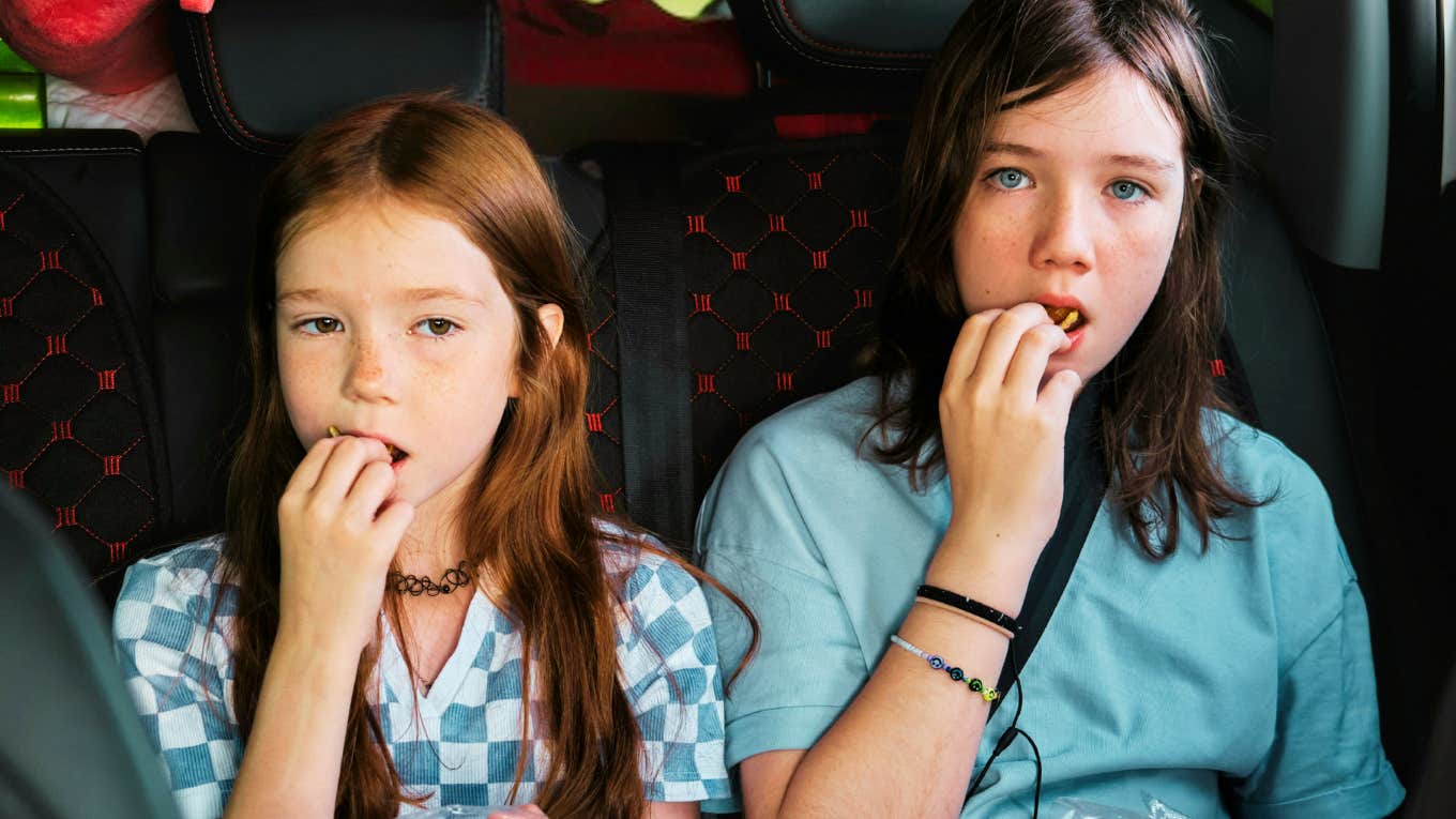 The Three-Step Plan For Turning A Selfish Kid Into A Grateful One Kids selfishly upset eating snacks in the back of the car during road trip.
