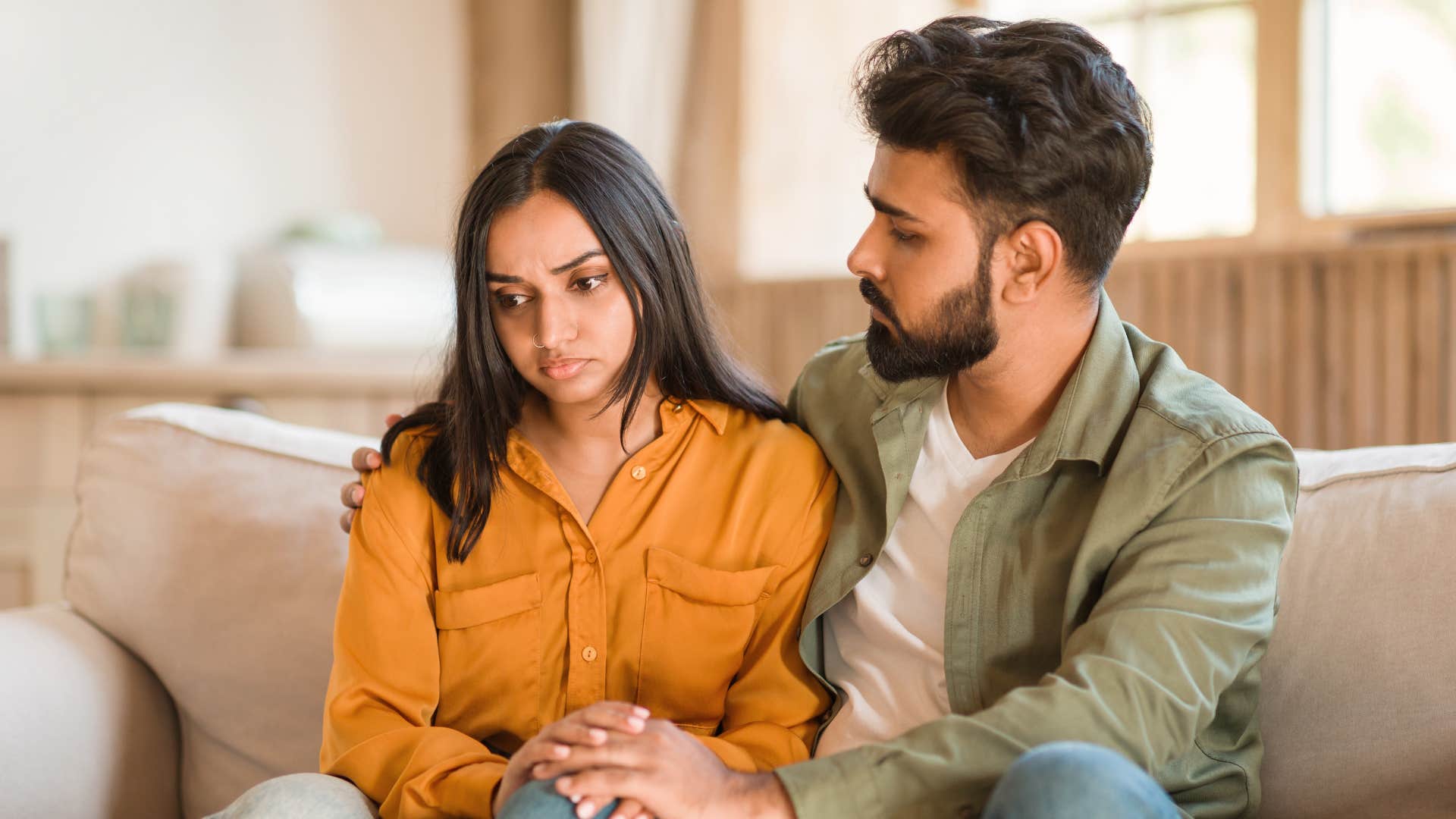 man trying to calm down woman on couch