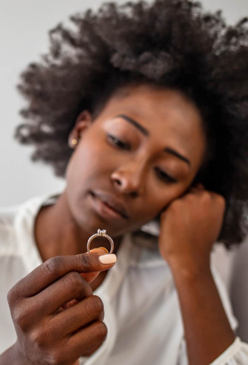 unhappy woman looking at engagement ring 