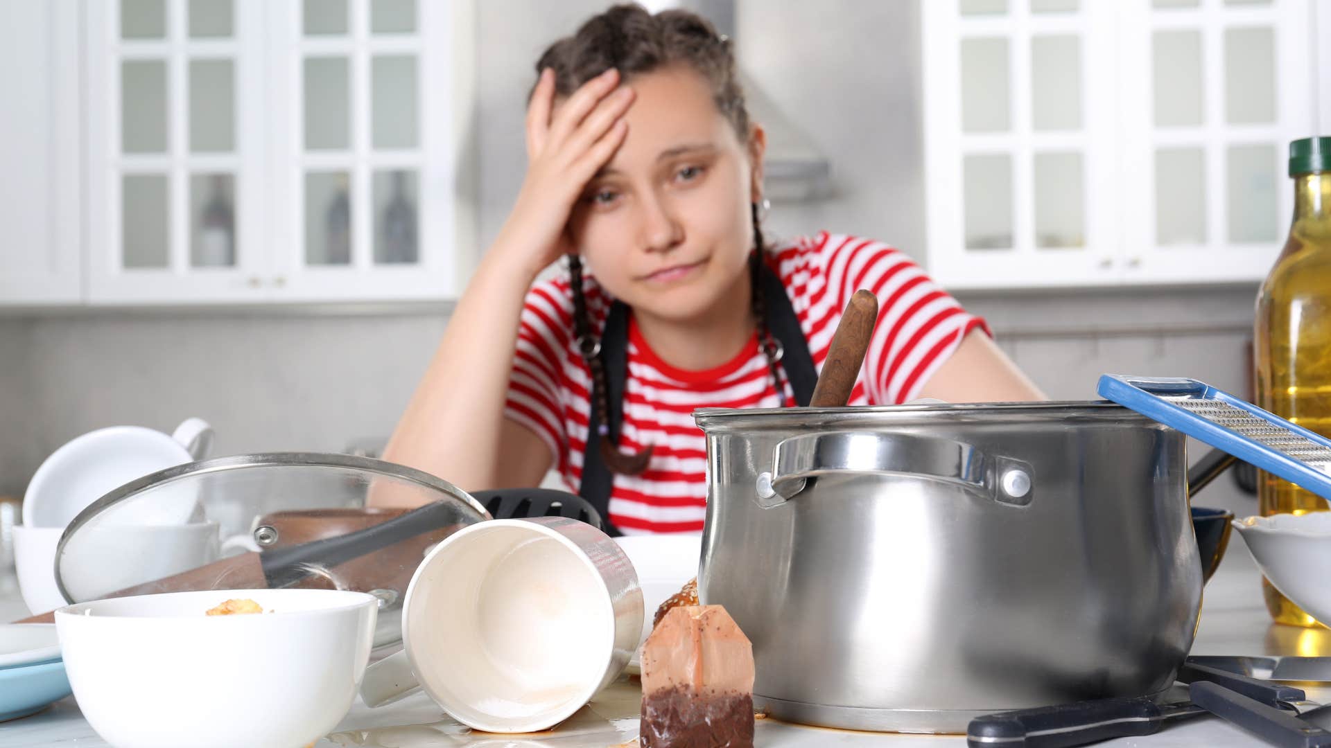 stressed woman overwhelmed by sink full of dirty dishes