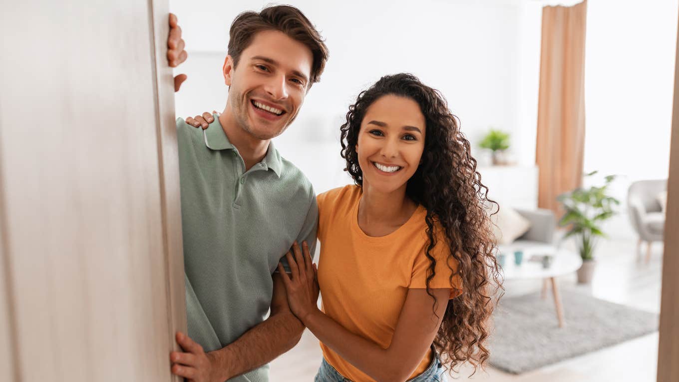 Ways People Can Tell Your House Is Dirty, Even If You Clean Up Before They Come Over couple inviting guests into their home unaware it is dirty
