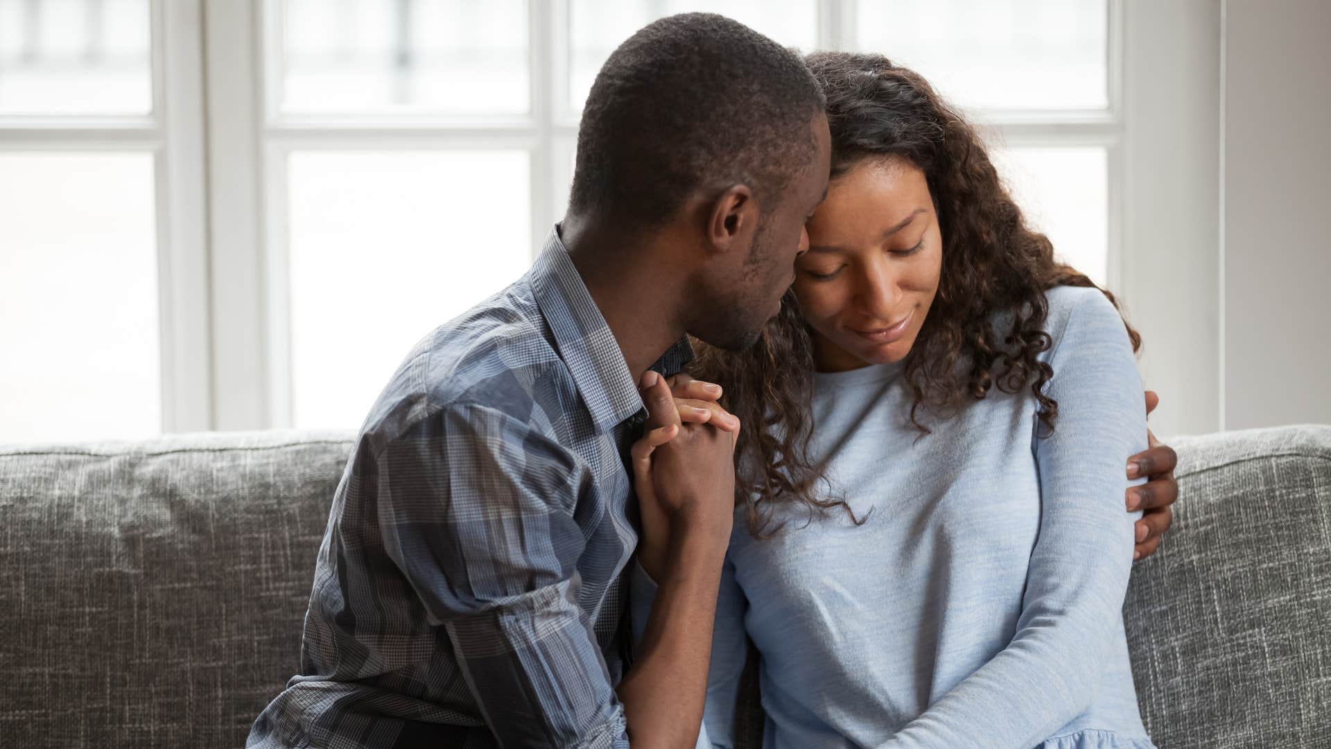 man providing a safe presence as he holds distraught woman in gray shirt 