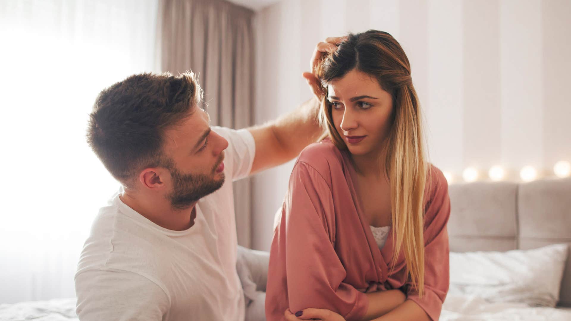woman grabbing her stomach in pain while man tries to comfort her