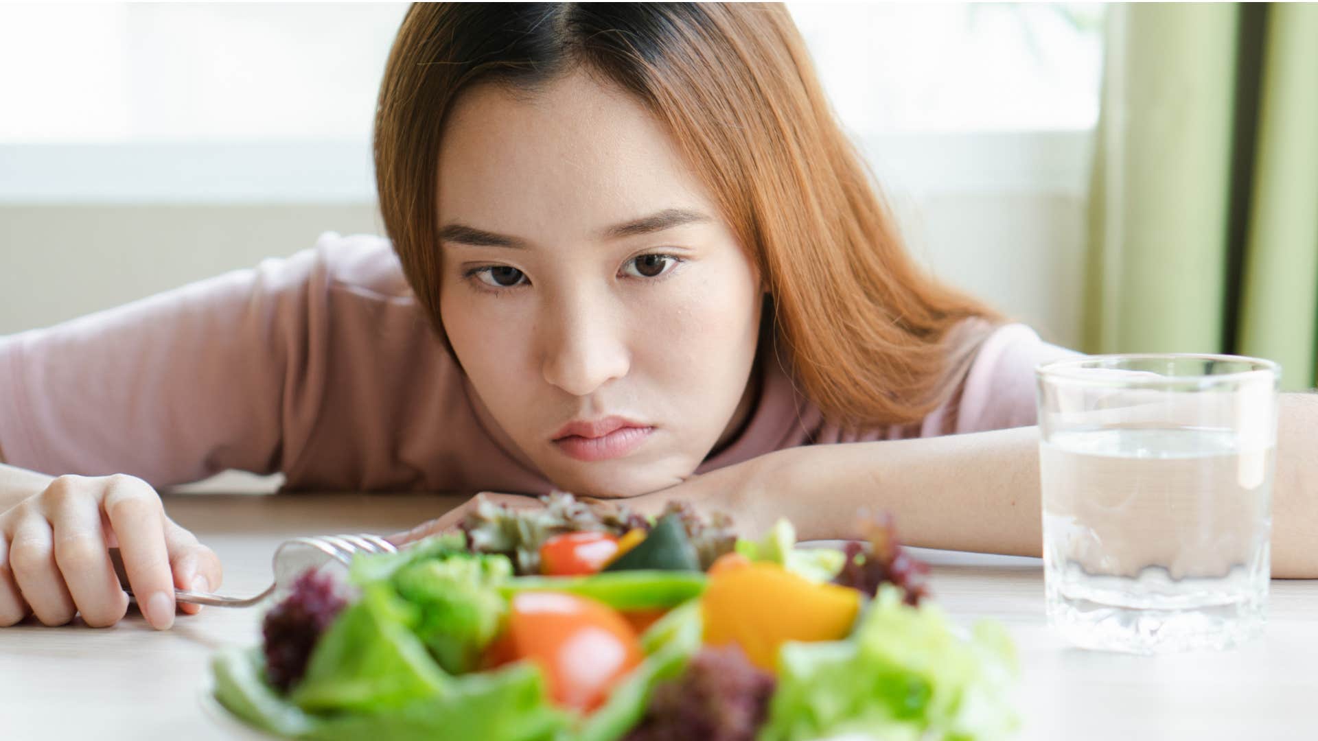 woman struggling to eat food in front of her