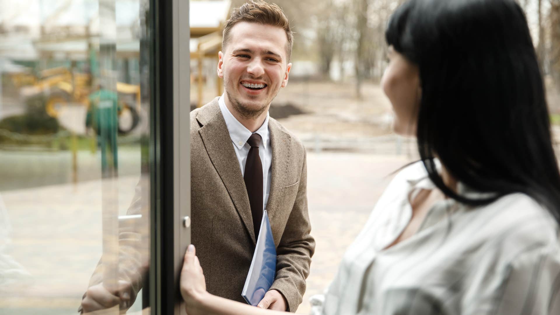 man holding the door for a woman and smiling