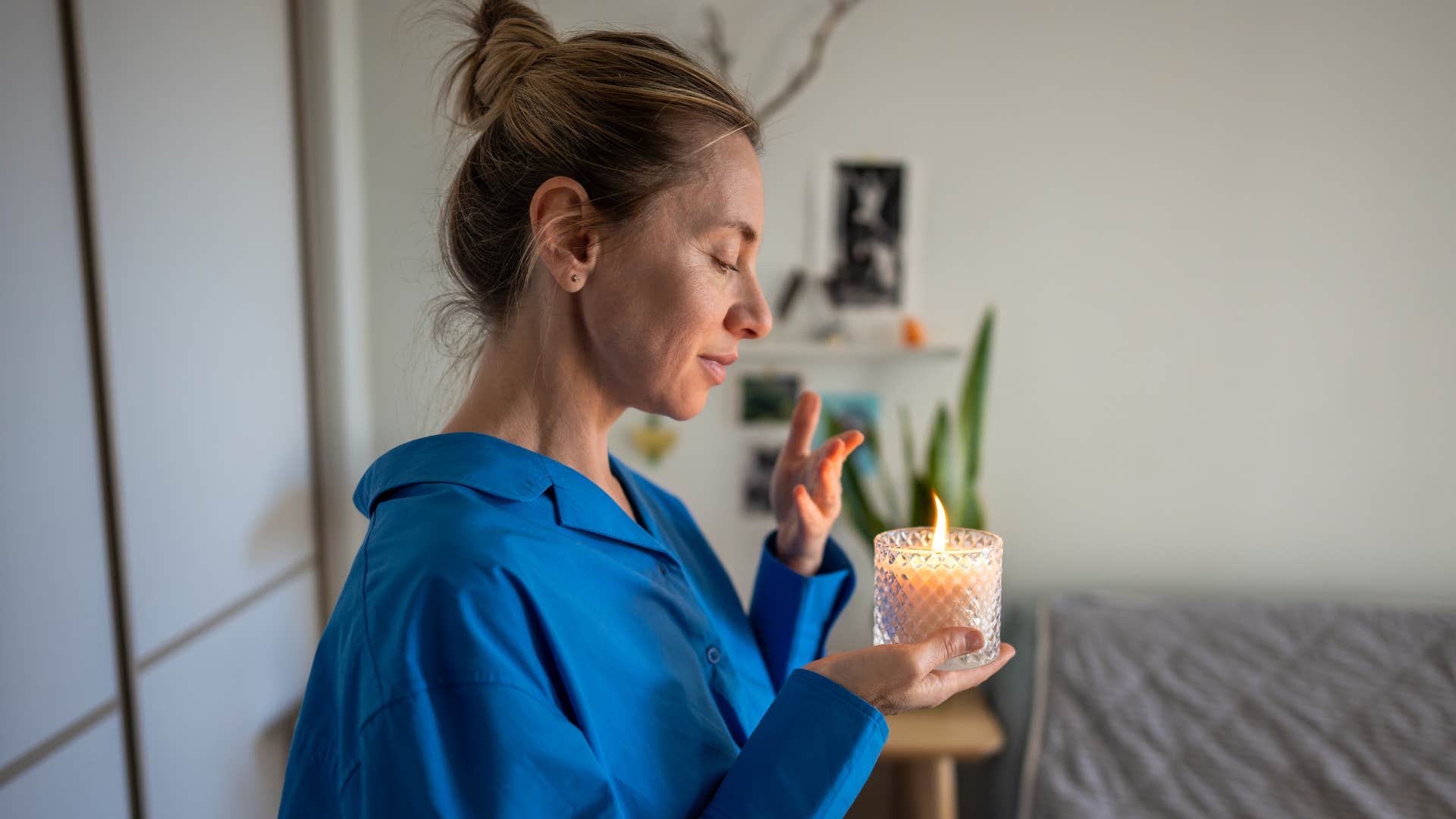 Woman holding a decorative candle in her home.