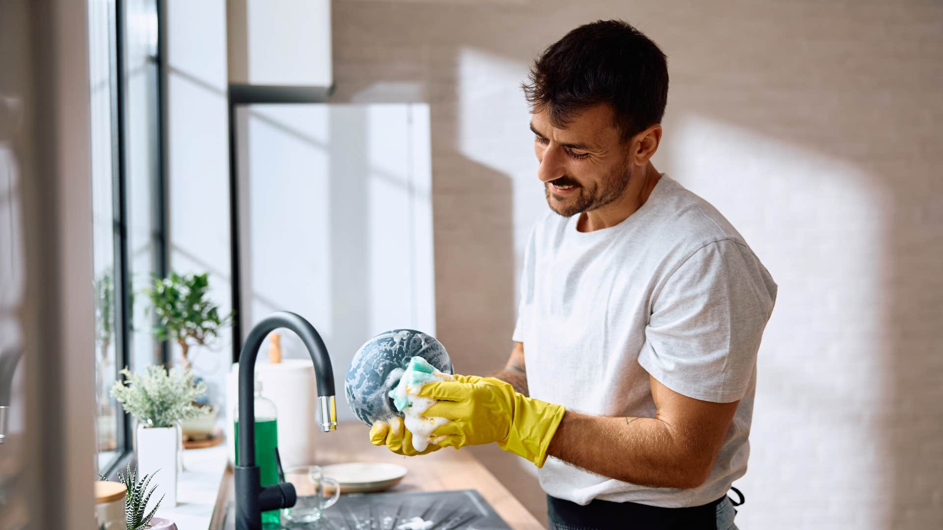 Man cleaning dirty dishes in his kitchen.