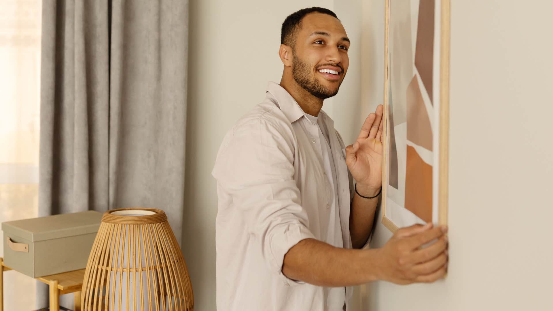Man setting up meaningless artwork or decor in his living room.