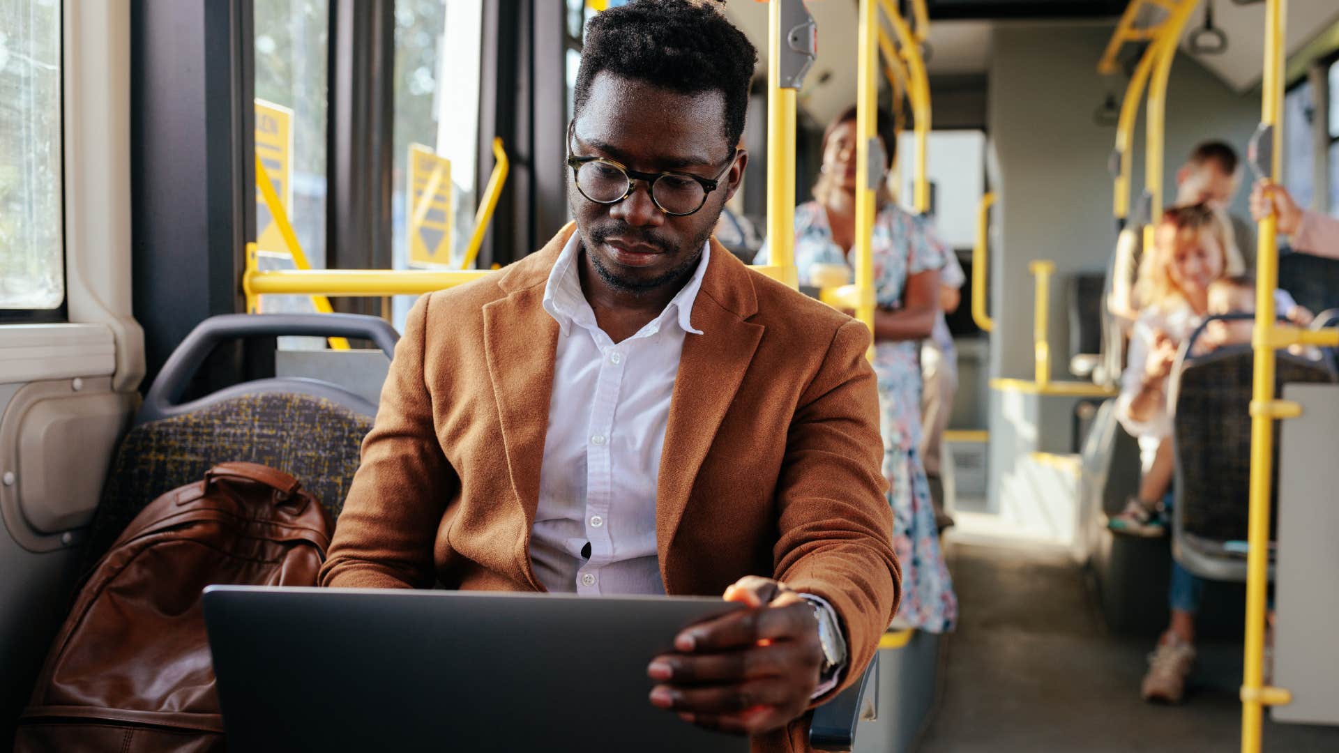 Man opting for public transportation and working on the bus.