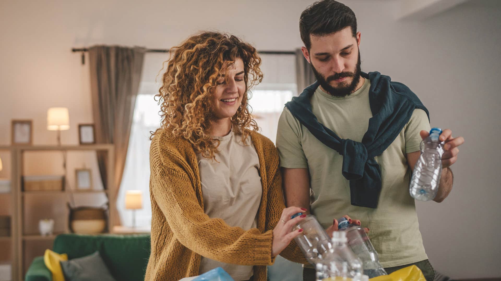 Couple smiling while reusing and recycling at home.