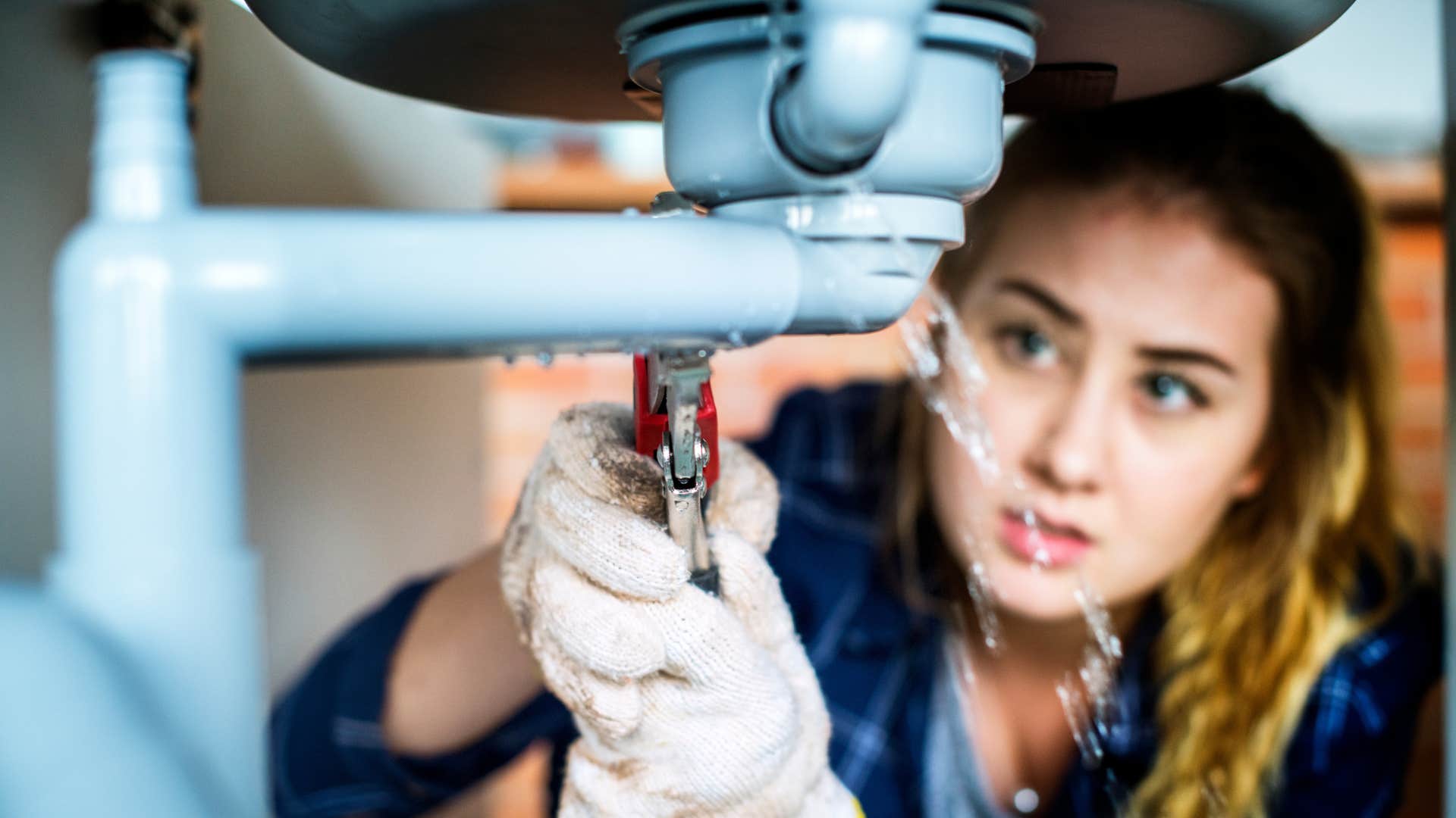 woman fixing her own sink instead of calling a plumber