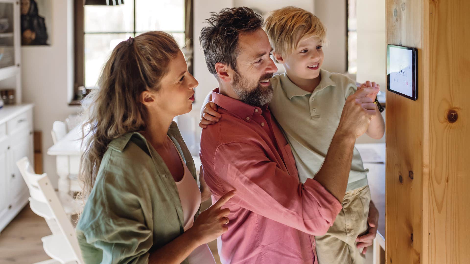 couple teaching their son how to use the thermostat