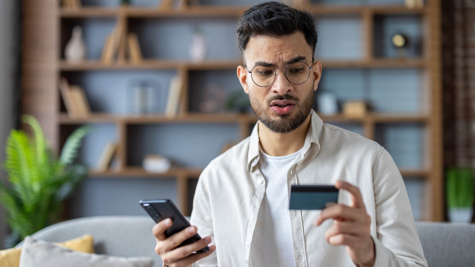 man looking at credit card stopping himself from purchasing something online
