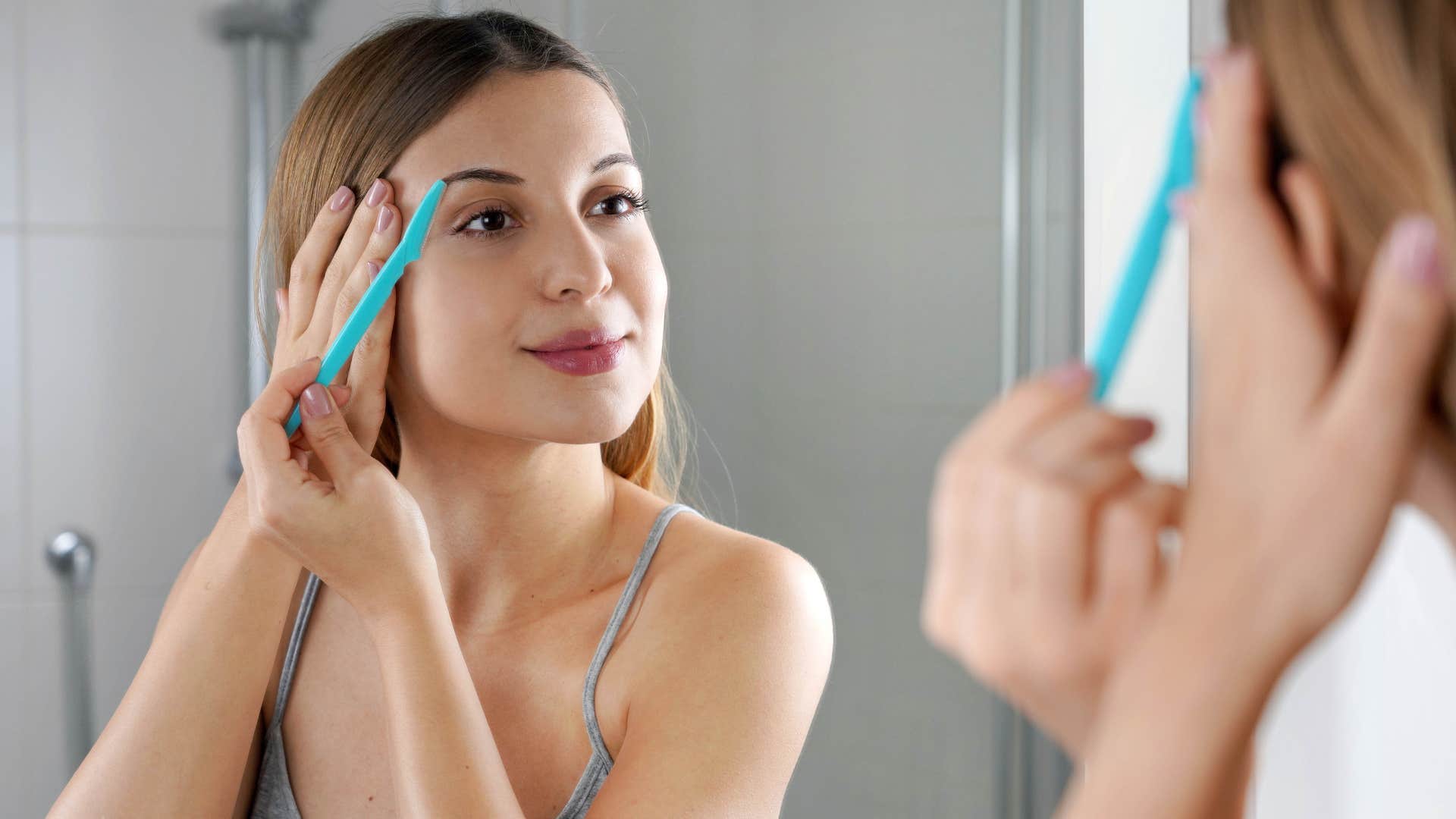 a young woman trims her eyebrows