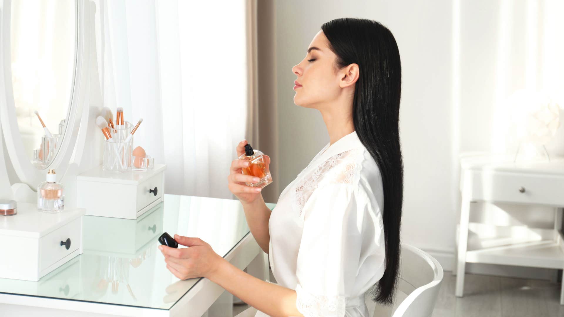 a woman sprays too much perfume on herself
