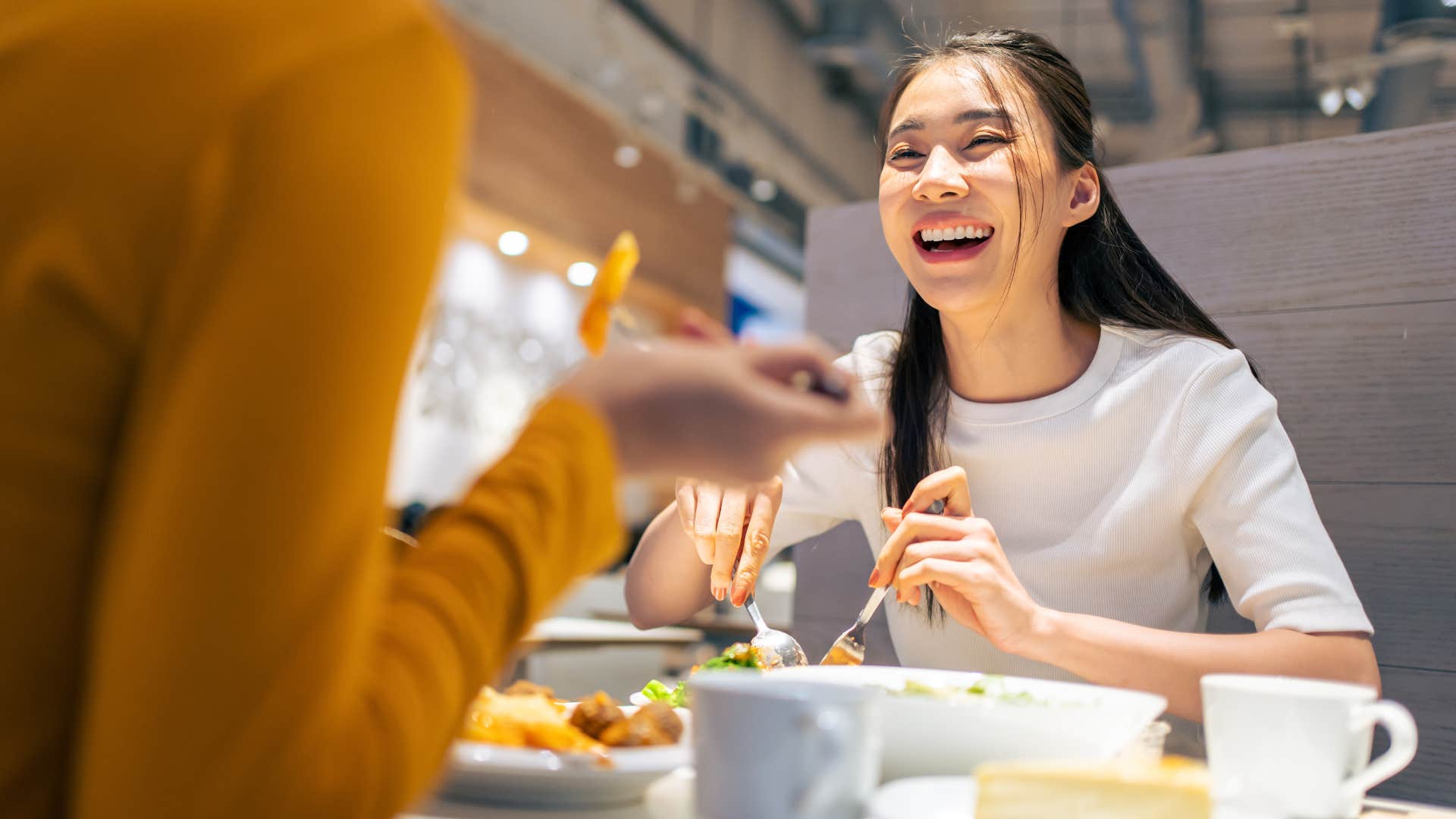 Woman smiling and interrupting someone at the dinner table