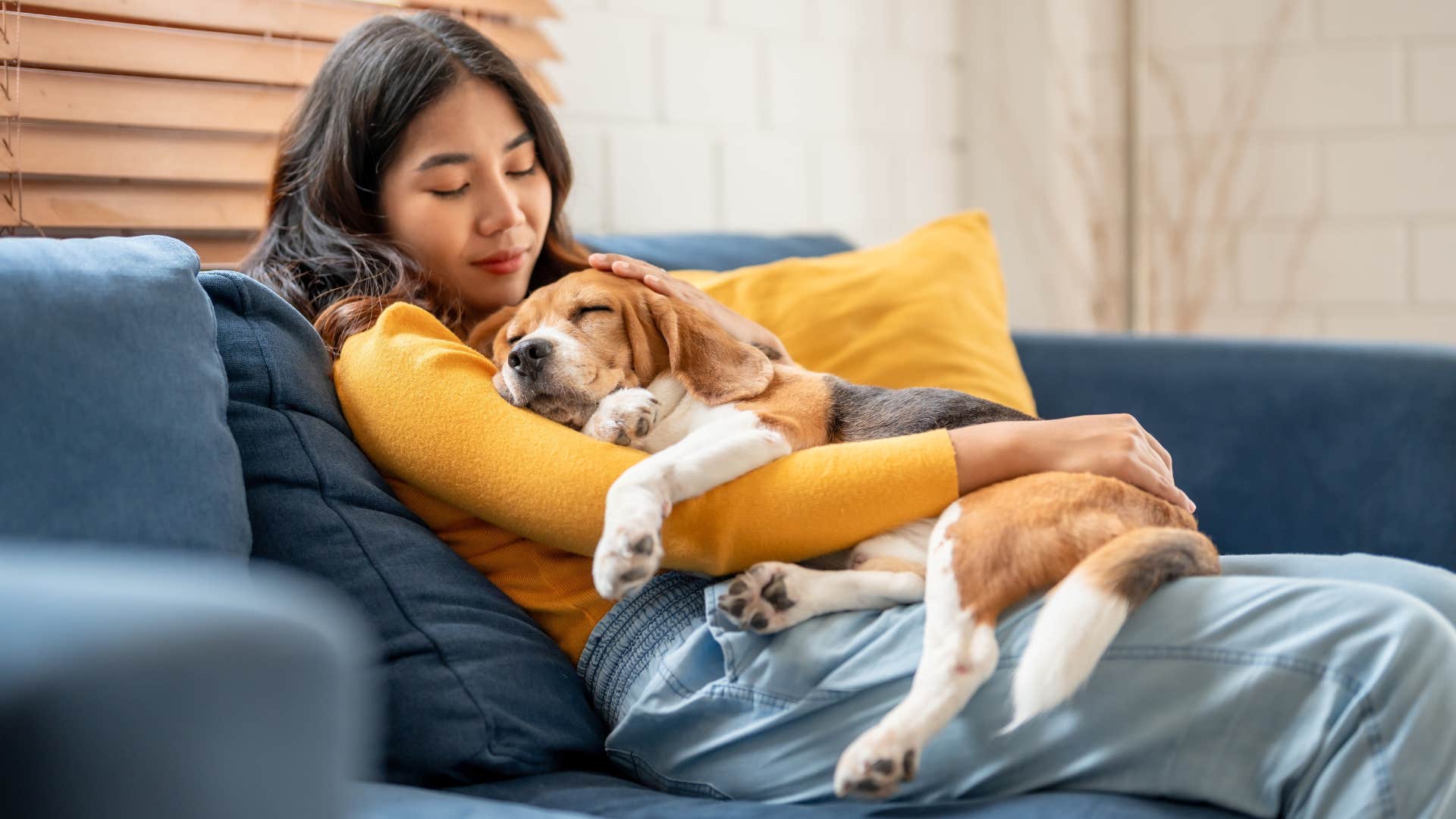 Woman hugging her dog who she feels calmer around on the couch.
