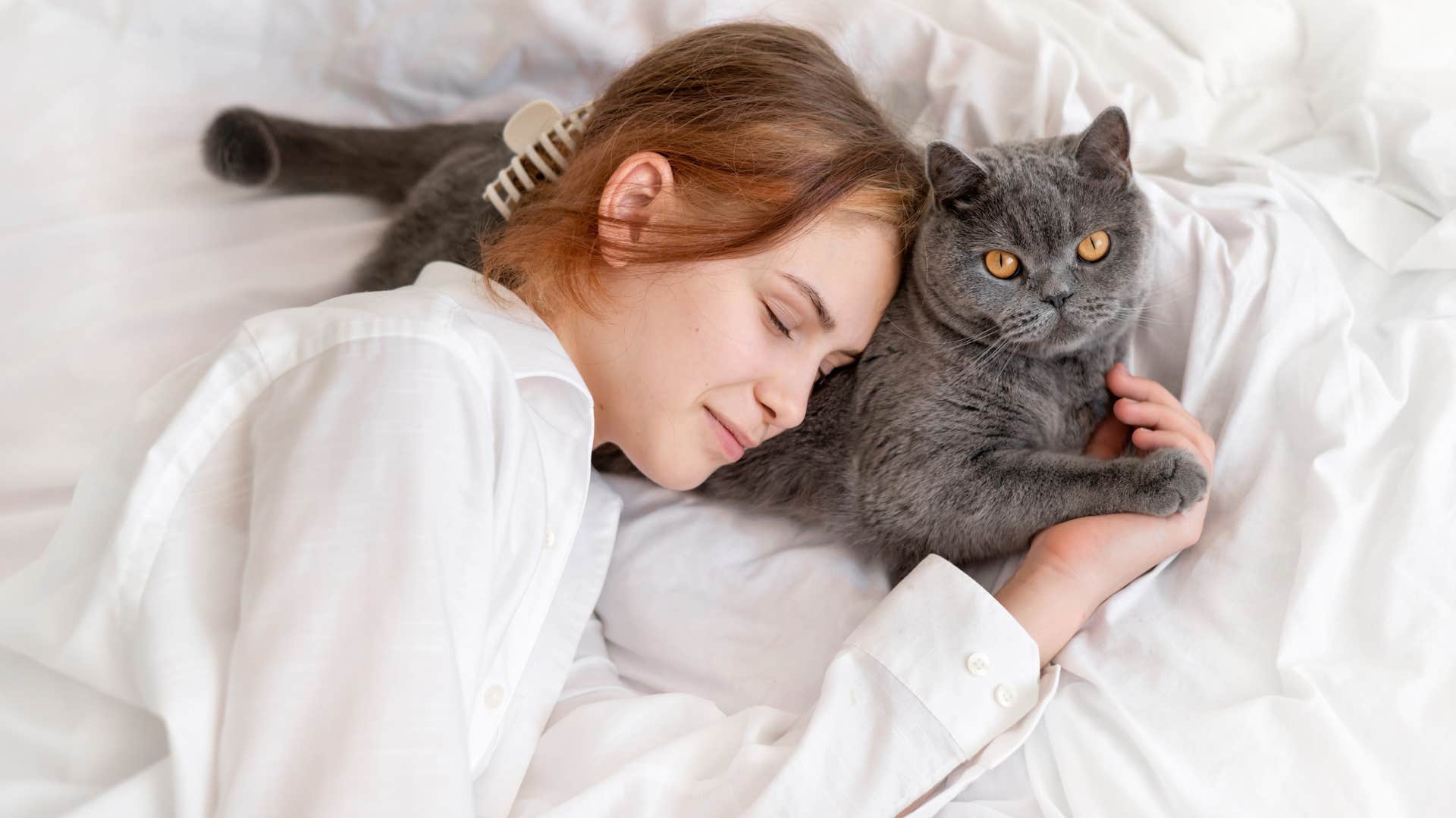 Woman laying with a cat who she can sleep better when they're nearby