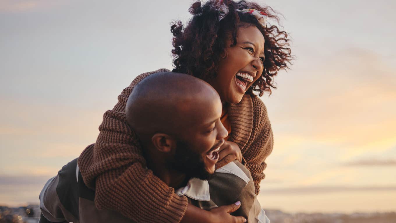 Happy couple laughing together on a beach.