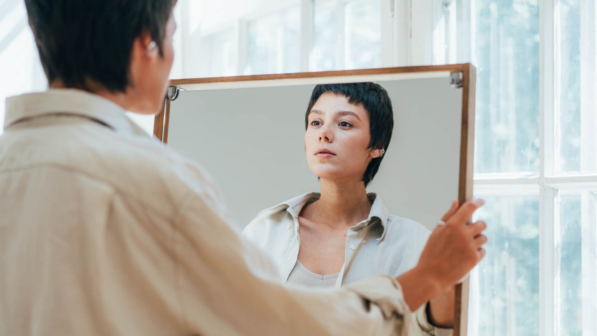 woman looking in mirror lacking love for herself