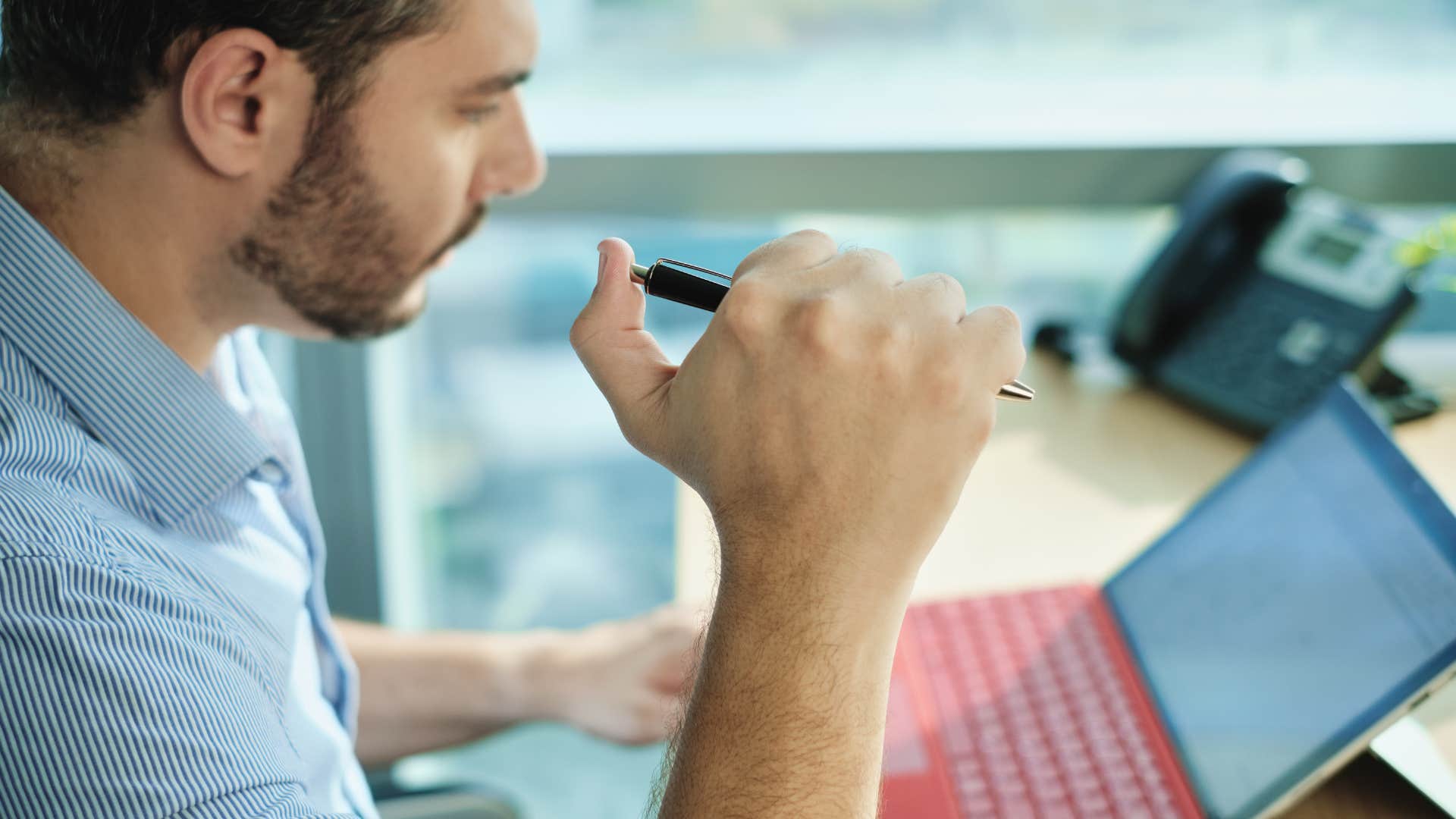 Man clicking pens at work.