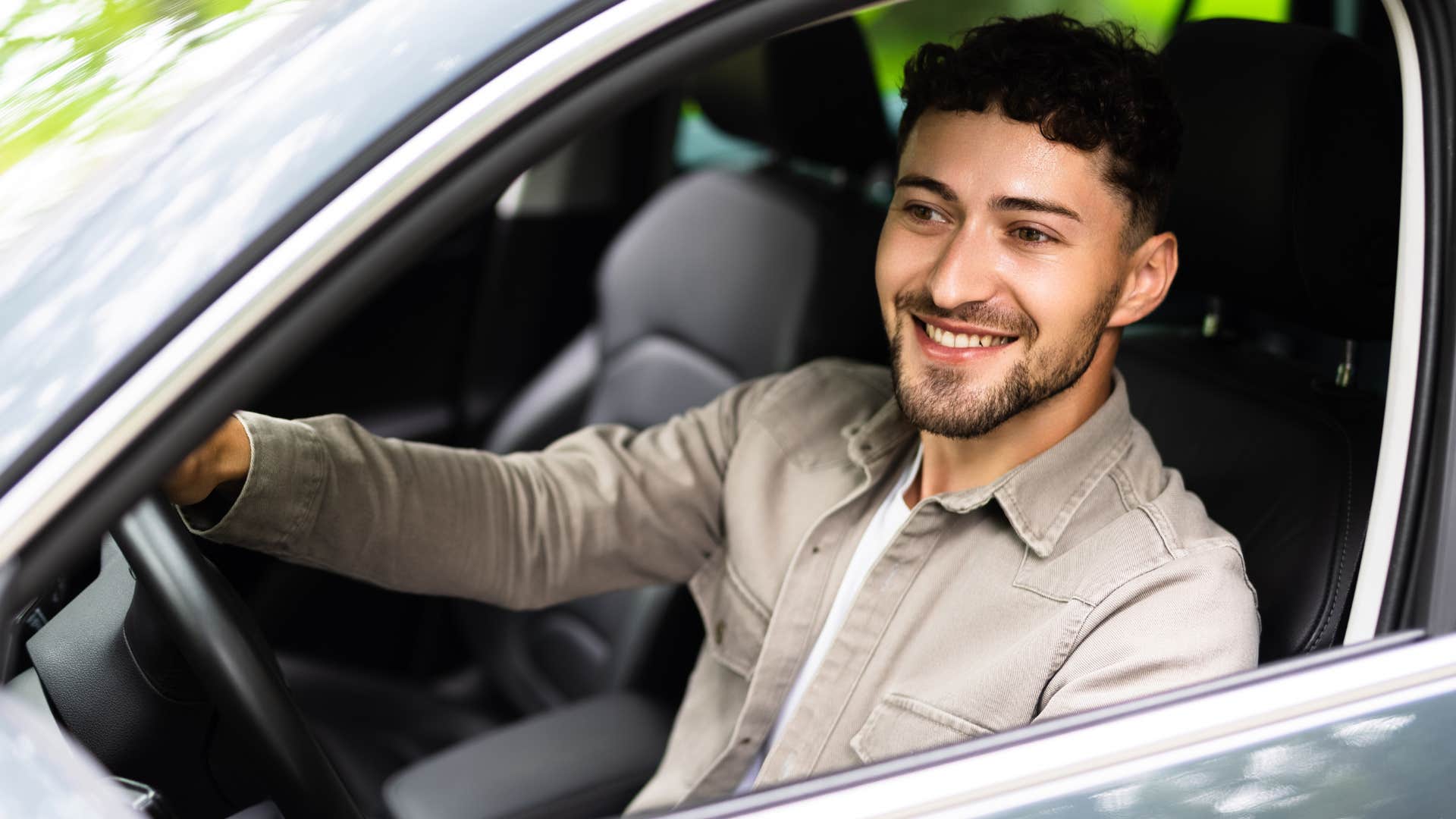 Man smiling and revving car engines in his car.