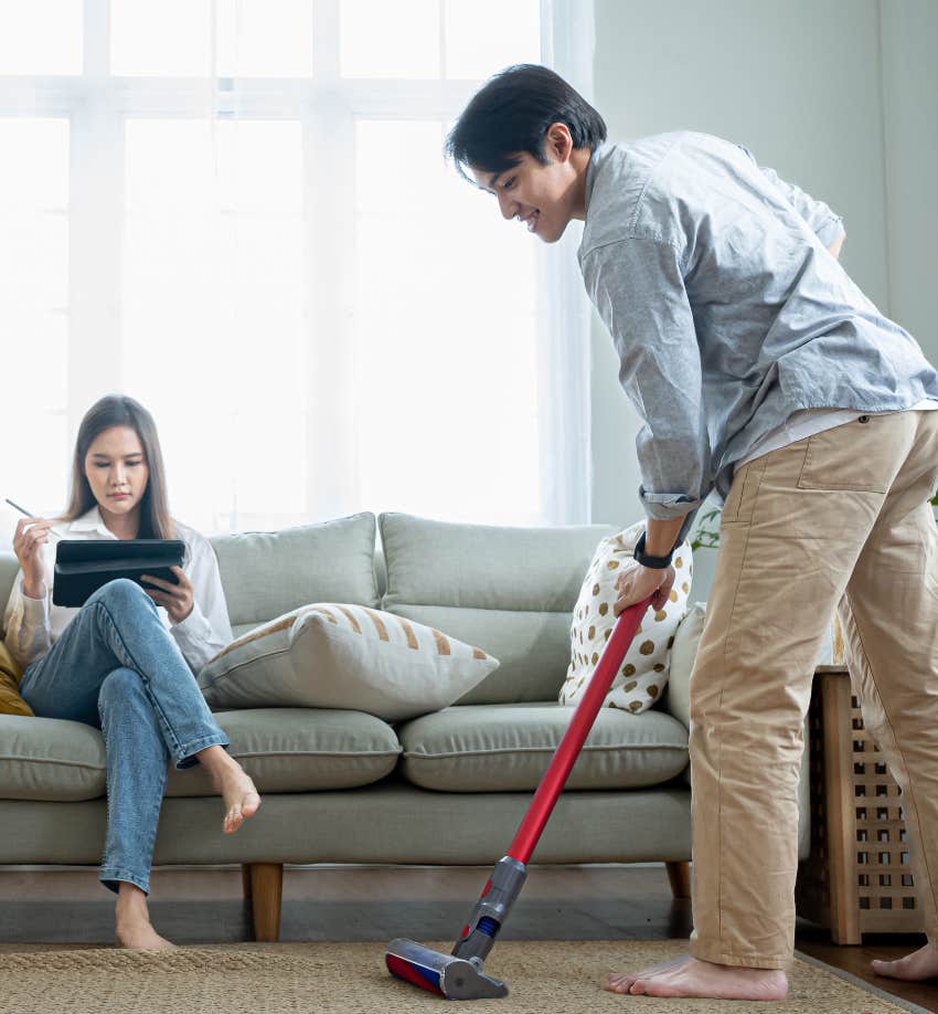 husband cleaning while his wife sits on sofa