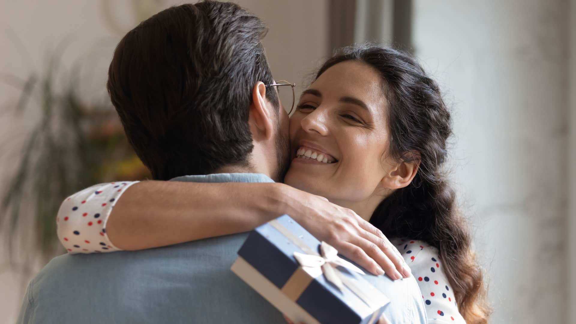 man celebrating her achievements as he gives her gift as she hugs him happily