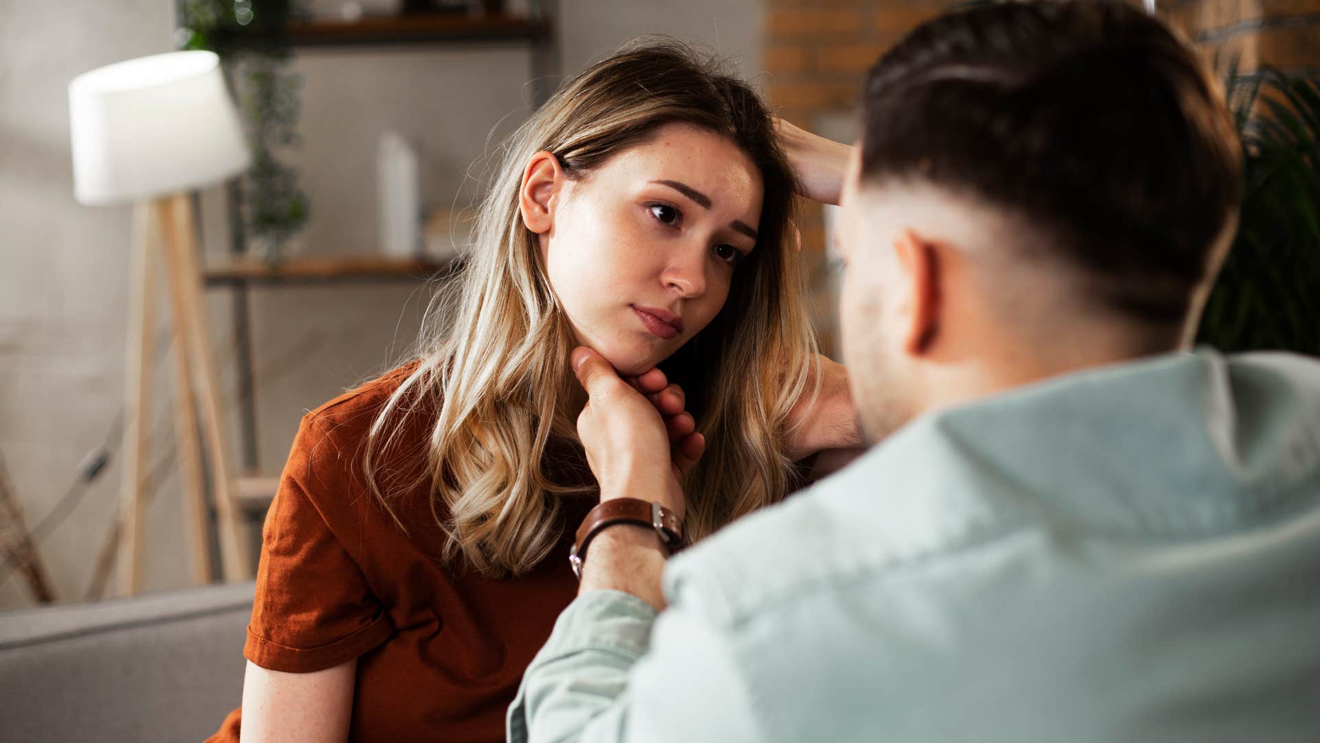 man offering emotional support to woman as she looks at him upset 